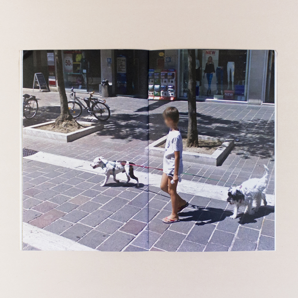 Attenti al Cane, Spread 13. Street View image of a child walking two leashed dogs and carrying a plastic bag. The child's face is blurred.