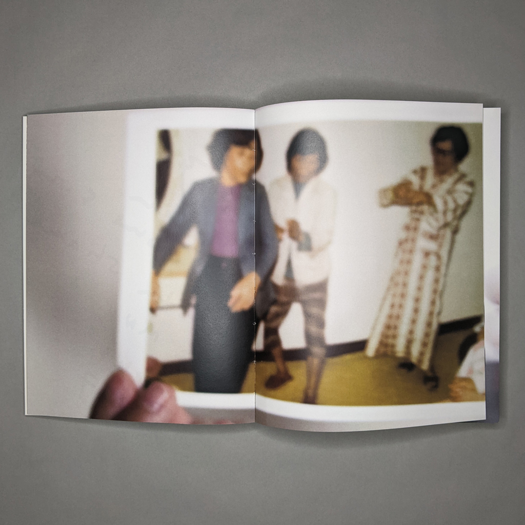 To My Unborn Child, inside spread: a full-bleed image of a hand holding a photograph. The photo shows three figures dancing.